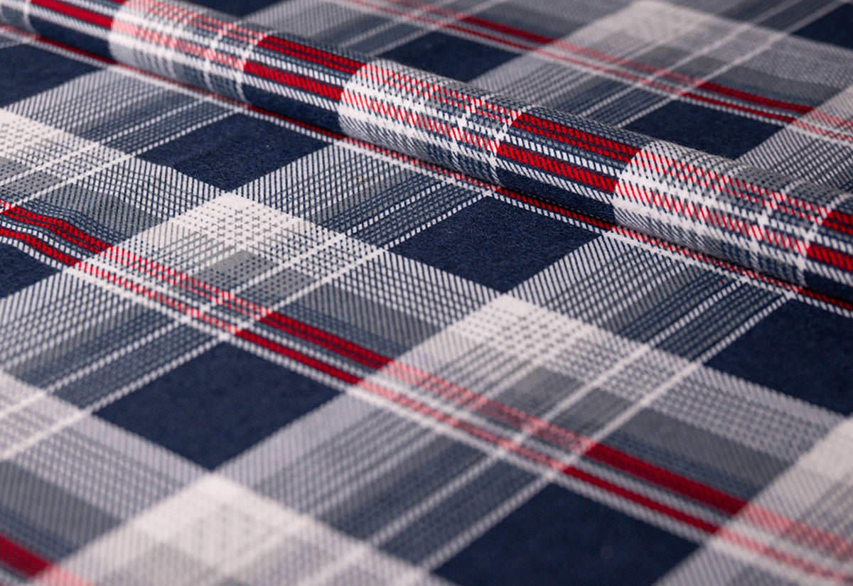Housse en flanelle à carreaux bleus : tissu en flanelle enroulé à motif tartan bleu marine, gris clair et blanc avec de fines lignes rouges, détail du tissu photographié de biais