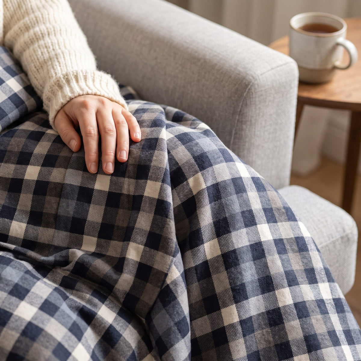 Gros plan : main sur la housse en flanelle grattée à carreaux gris